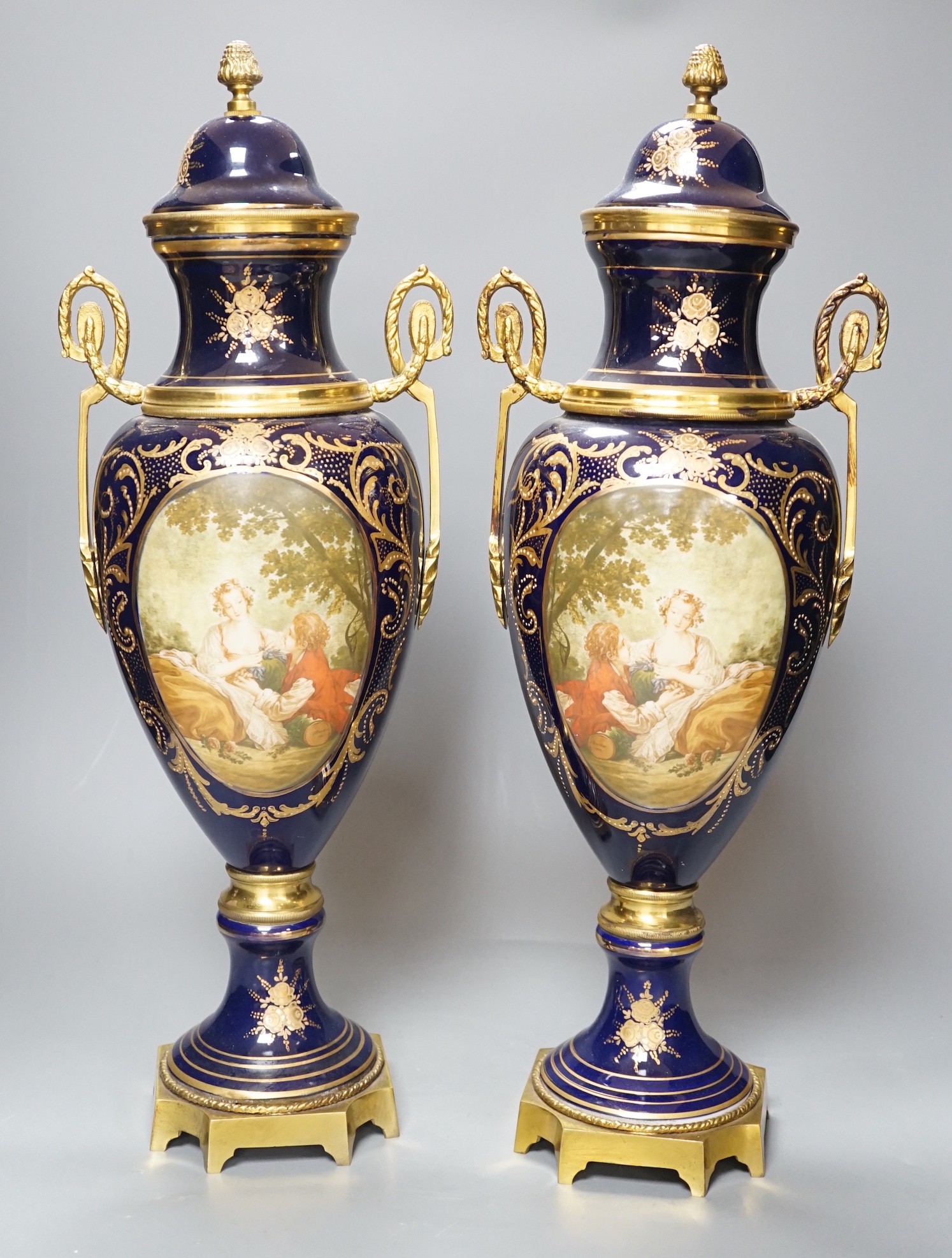 A pair of Sevres style urns and covers, with gilt metal mounts, 50 cms high